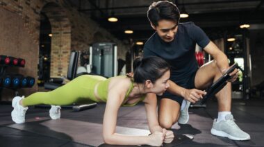 A person planking with their coach showing their stats.