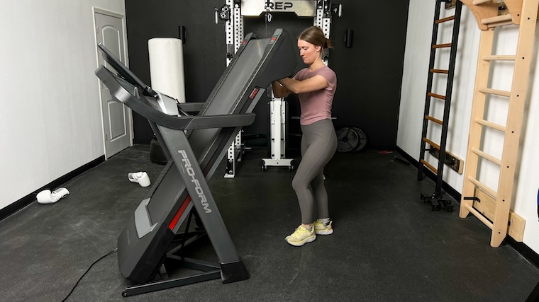A BarBend tester unfolding the ProForm Pro 9000 treadmill